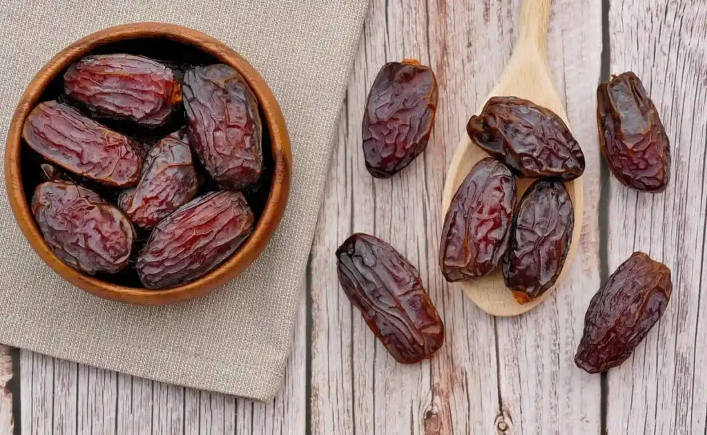 Premium dates in a wooden bowl and spoon, highlighting a natural, science-backed pre-workout snack for sustained energy and performance.